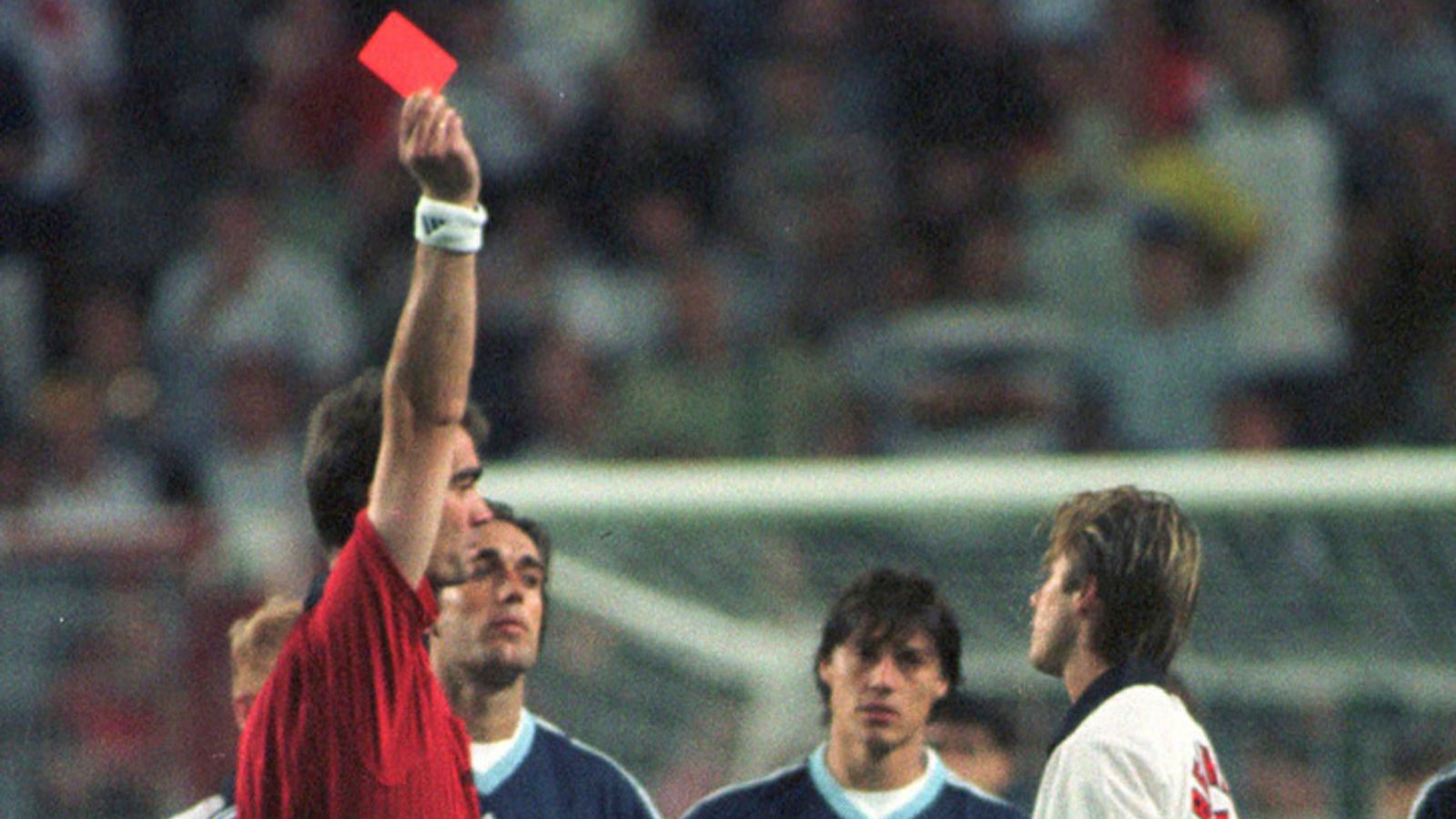 FILE - England's David Beckham receives a red card from Danish referee Kim Milton Nielsen for kicking Argentina's Diego Simeone, during England's World Cup second round soccer match against Argentina, in Saint Etienne, France on June 30, 1998. England lost on penalties after the match ended 2-2. A four-part Netflix series, "Beckham," explores Beckham’s upbringing and his triumphs on the field, but perhaps the most difficult part was revisiting his painful sending off during England’s World Cup m