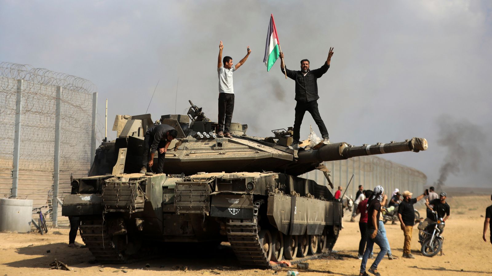 Palestinians wave their national flag by a destroyed Israeli tank at the Gaza Strip fence east of Khan Younis. Pic: AP
